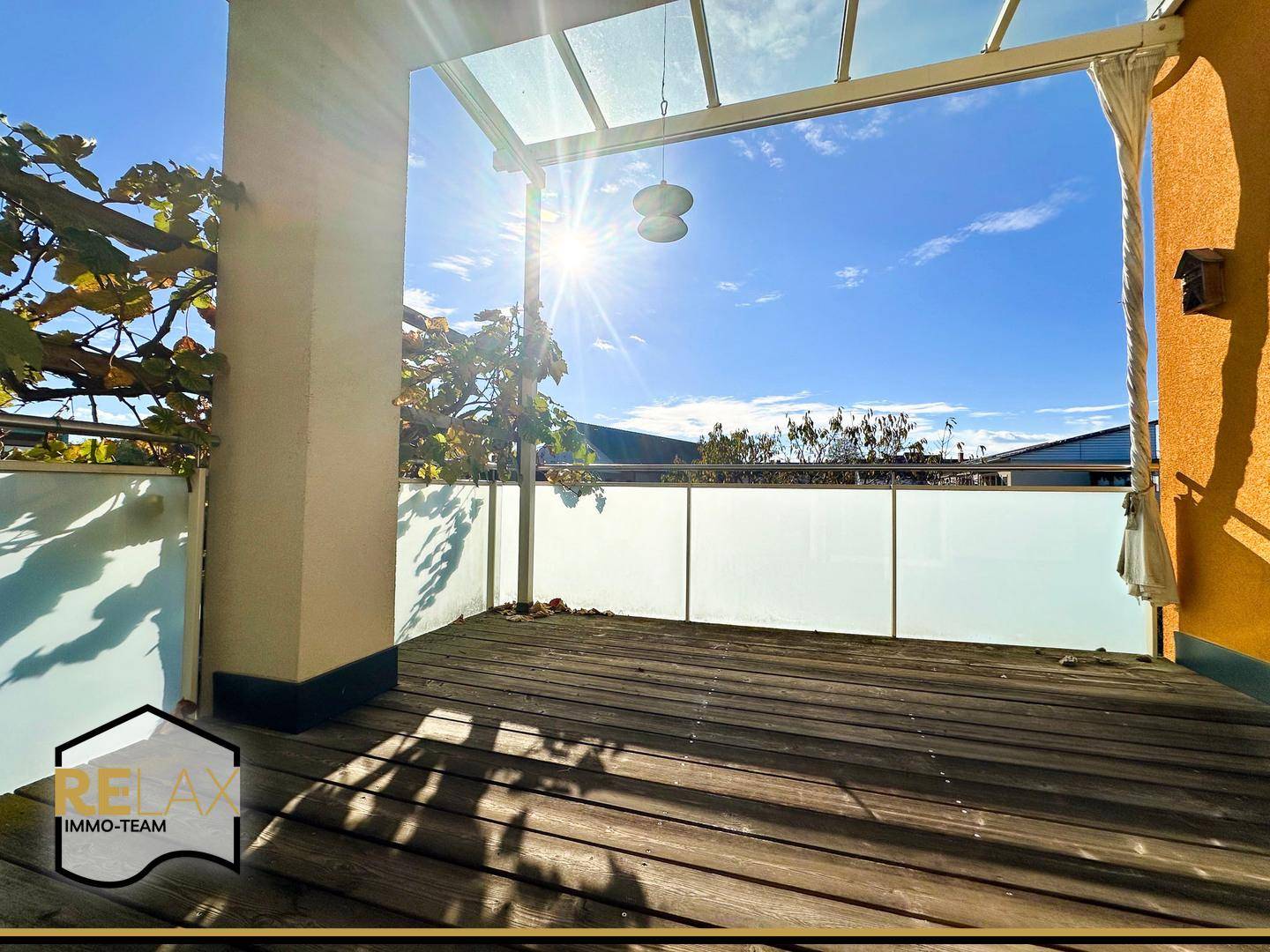 Sonniger Balkon mit Holzboden und Milchglasbrüstung, perfekt für entspannte Momente im Freien.