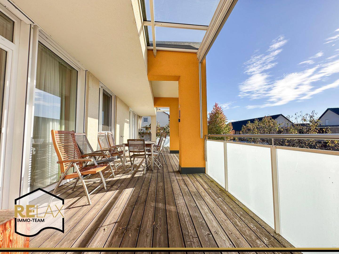 Langer Balkon mit Holzboden, Sitzgelegenheiten und Blick auf die Umgebung.