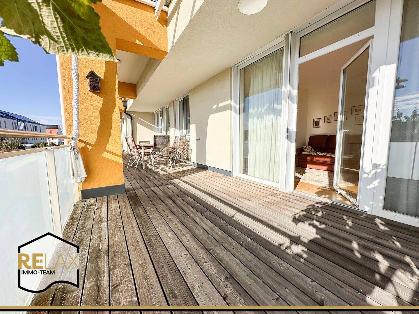 Geräumiger Balkon mit Holzboden und Zugang zum hellen Innenbereich der Wohnung.