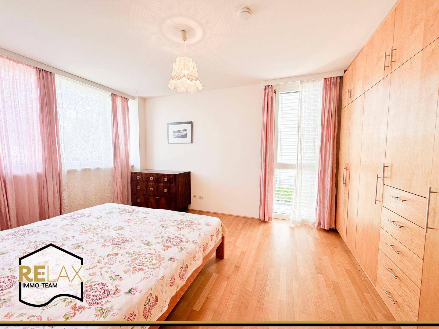 Gemütliches Schlafzimmer mit Holzboden, Einbauschränken und Zugang zum Balkon.
