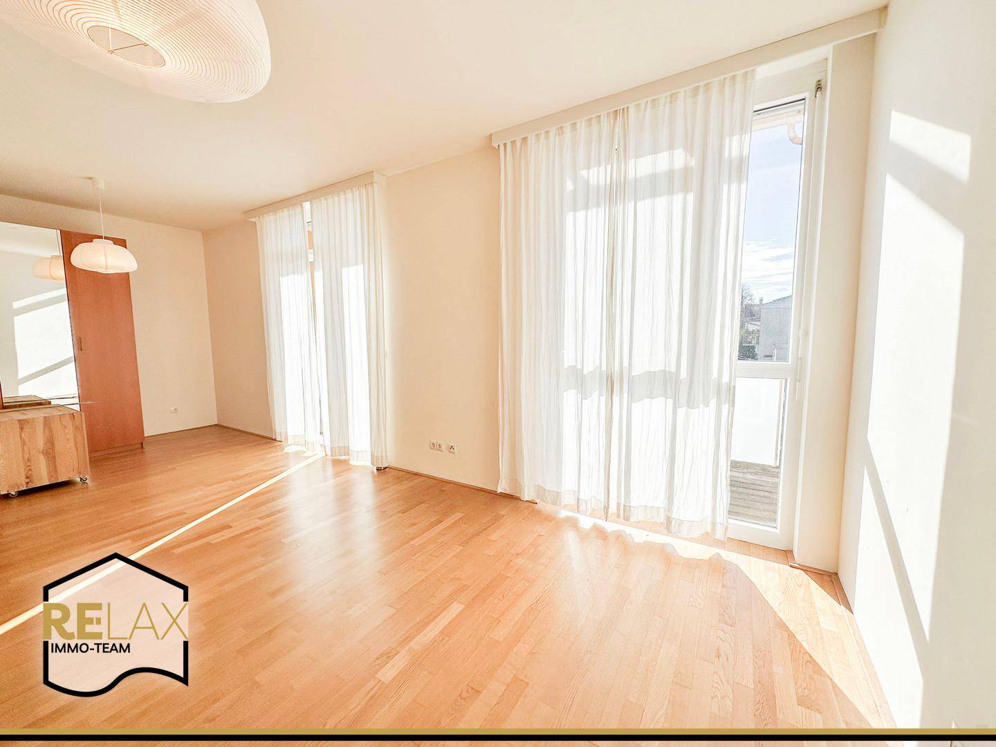 Helles Wohnzimmer mit Holzboden und Zugang zu einem Balkon, ideal für sonnige Tage.
