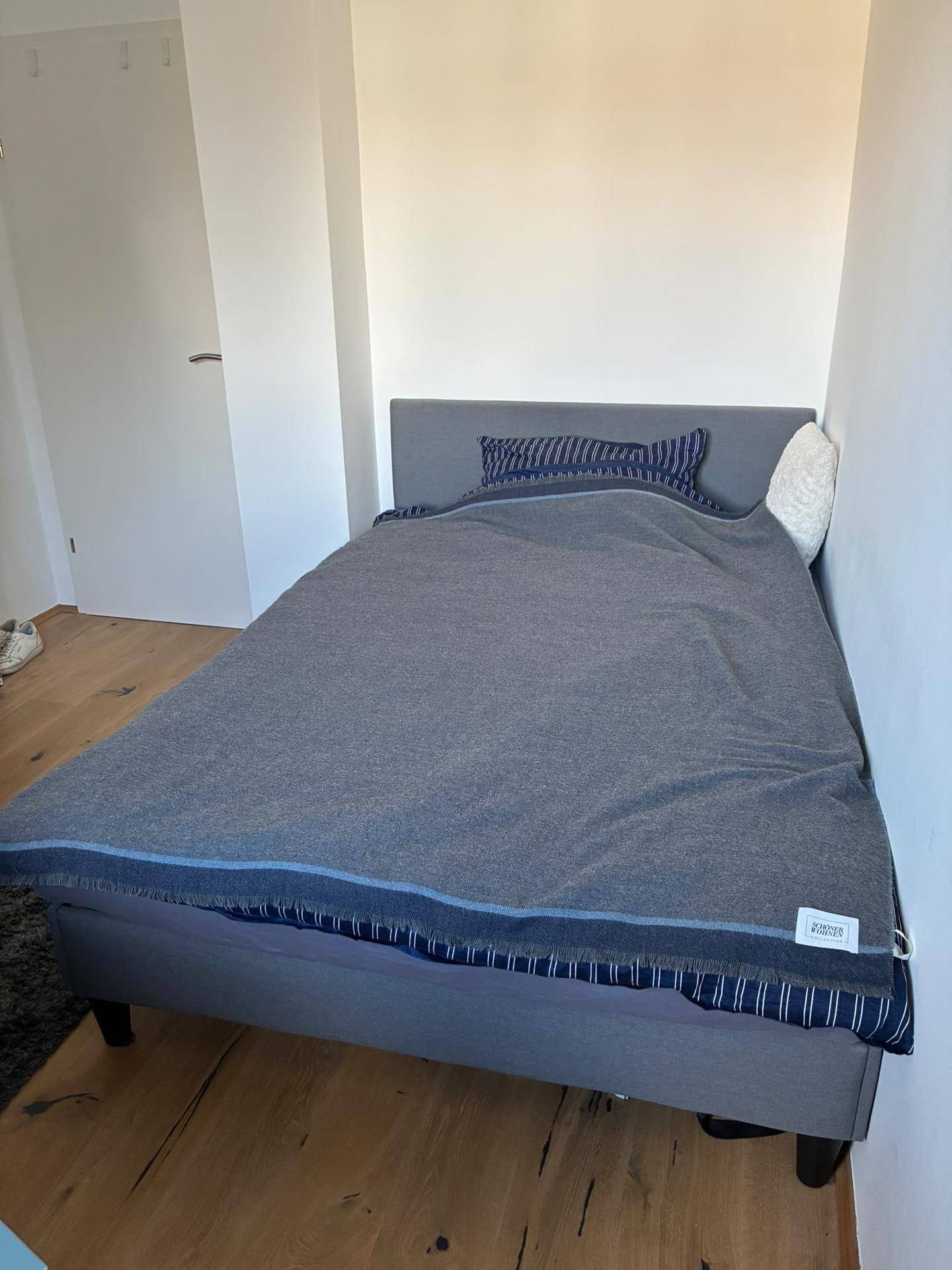 Gemütliches Schlafzimmer mit einem Einzelbett und Holzboden, die Wände sind hell gestrichen.