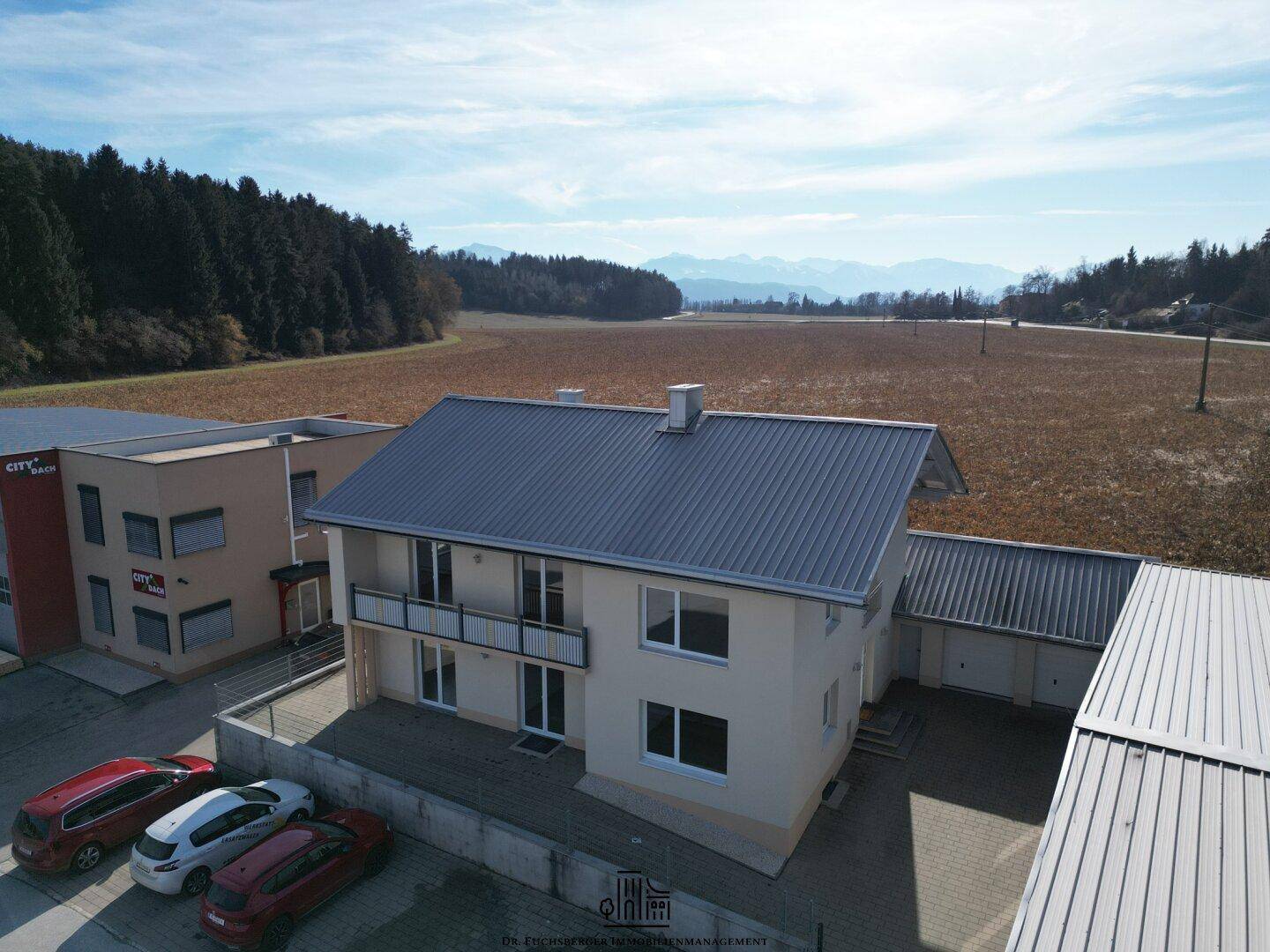 Modernes Einfamilienhaus mit Balkonen, Doppelgarage und weitem Blick auf Felder und Berge.