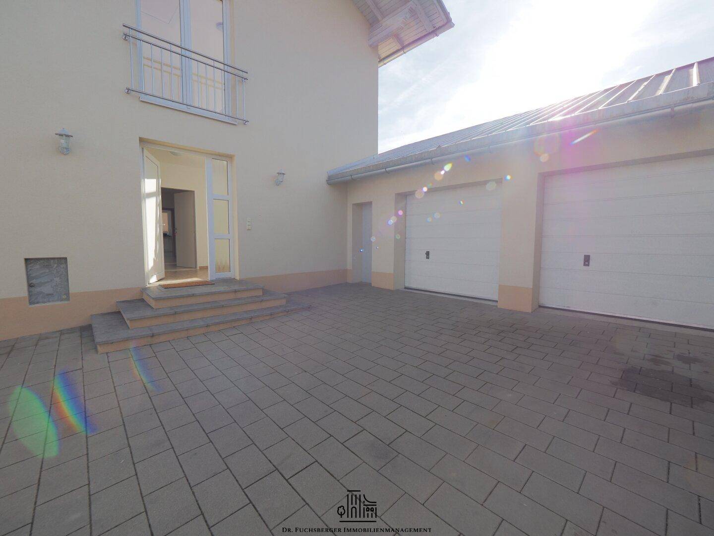 Eingangsbereich des Hauses mit gepflastertem Vorplatz und zwei Garagen, bietet bequemen Zugang.