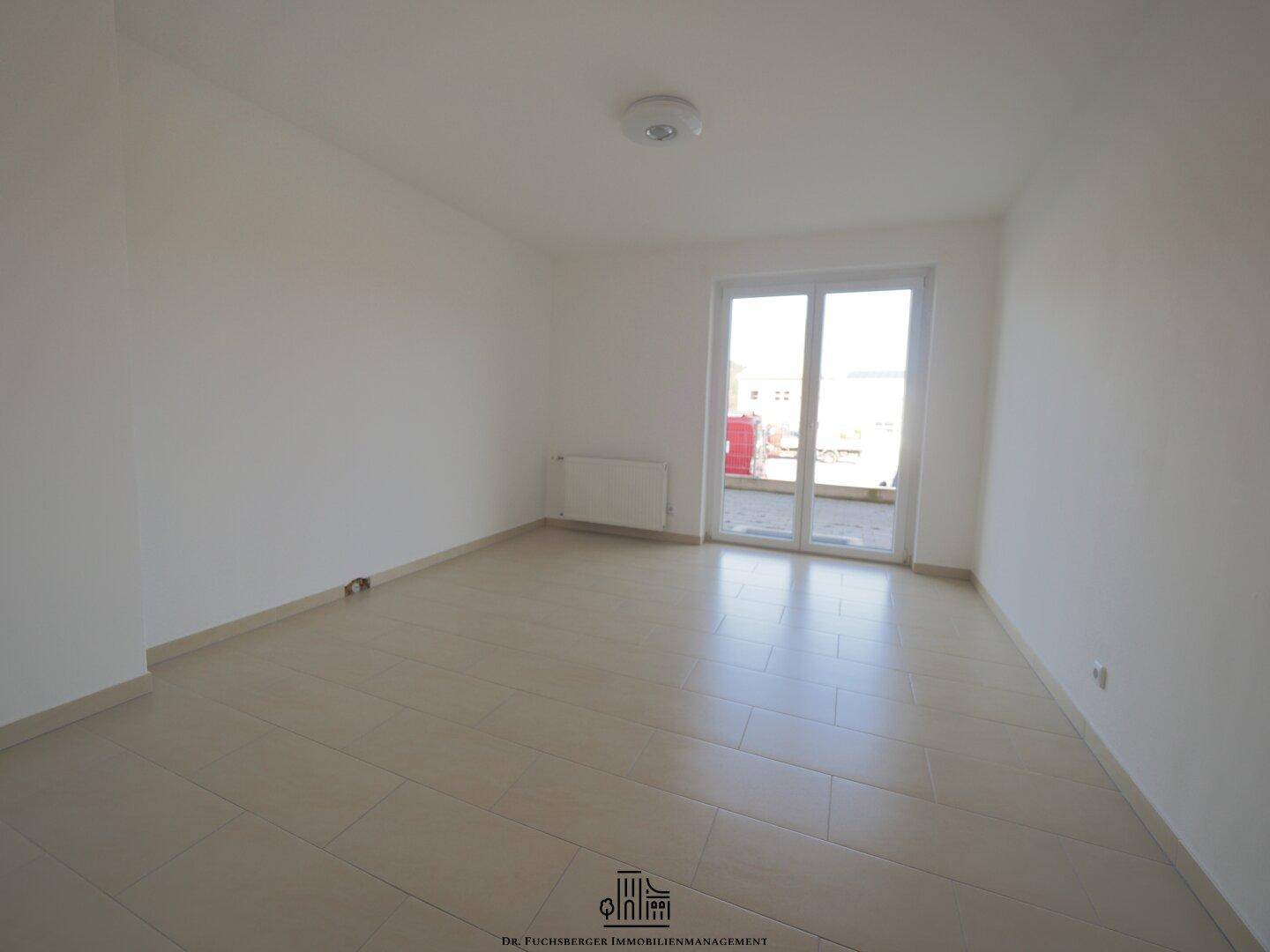 Helles Schlafzimmer mit Fliesenboden und Zugang zu einer Terrasse, bietet eine angenehme Wohnatmosphäre.