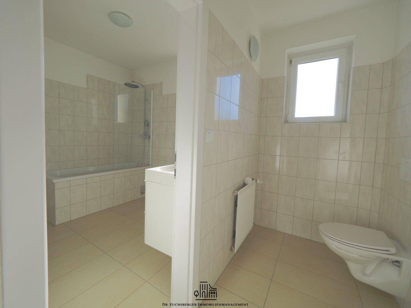 Modernes Badezimmer mit hellen Fliesen, Badewanne, Dusche und WC, bietet Komfort und Funktionalität.