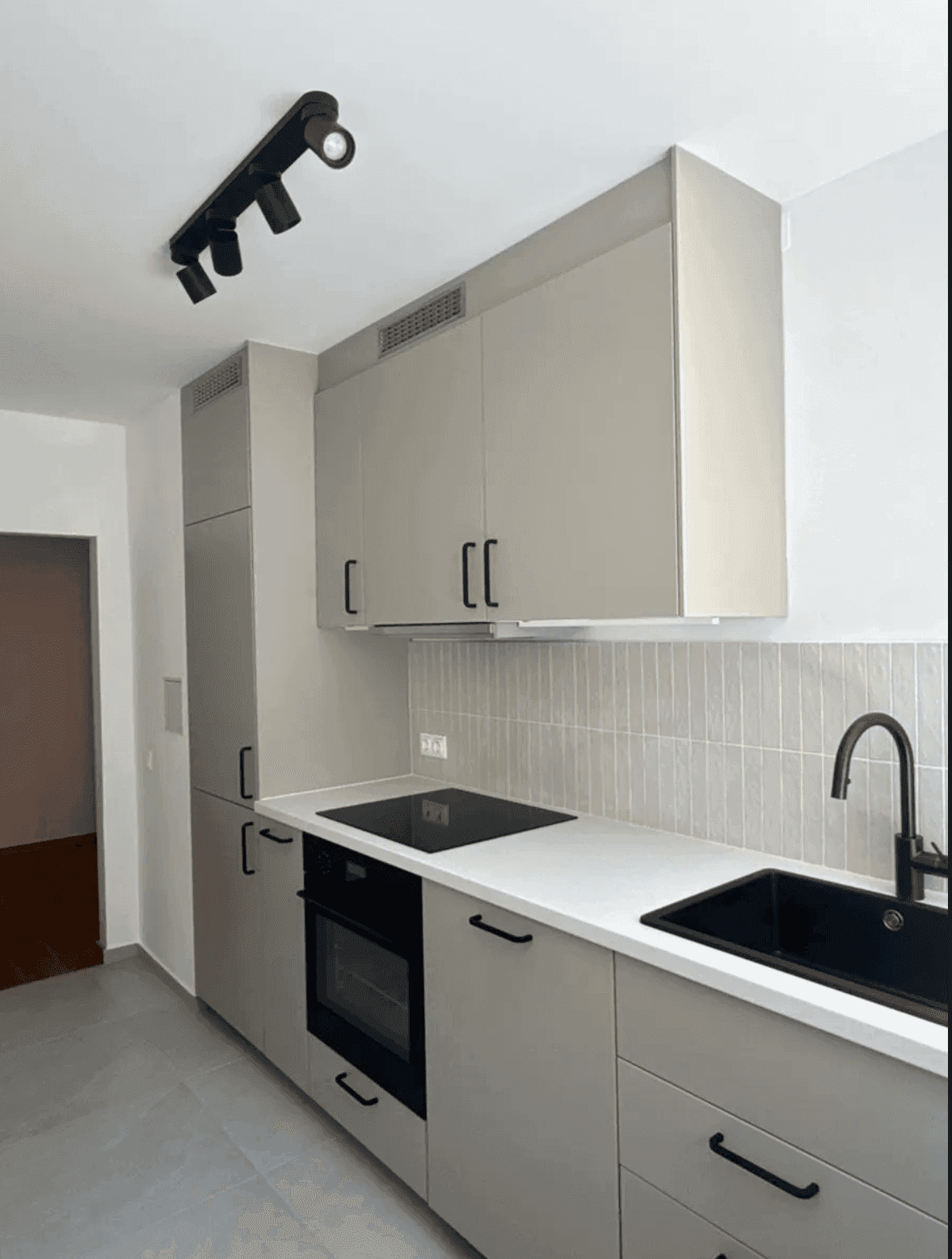 Detailansicht der modernen Küche mit Induktionskochfeld, Backofen und integrierter Spüle.