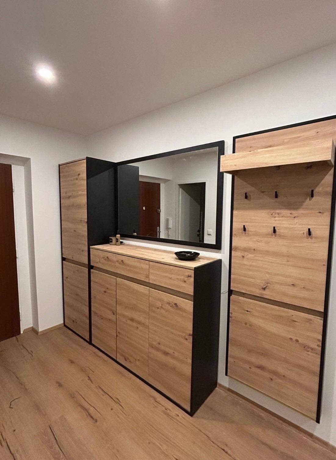 Moderner Eingangsbereich mit Holzmöbeln, großem Spiegel und integrierter Garderobe.