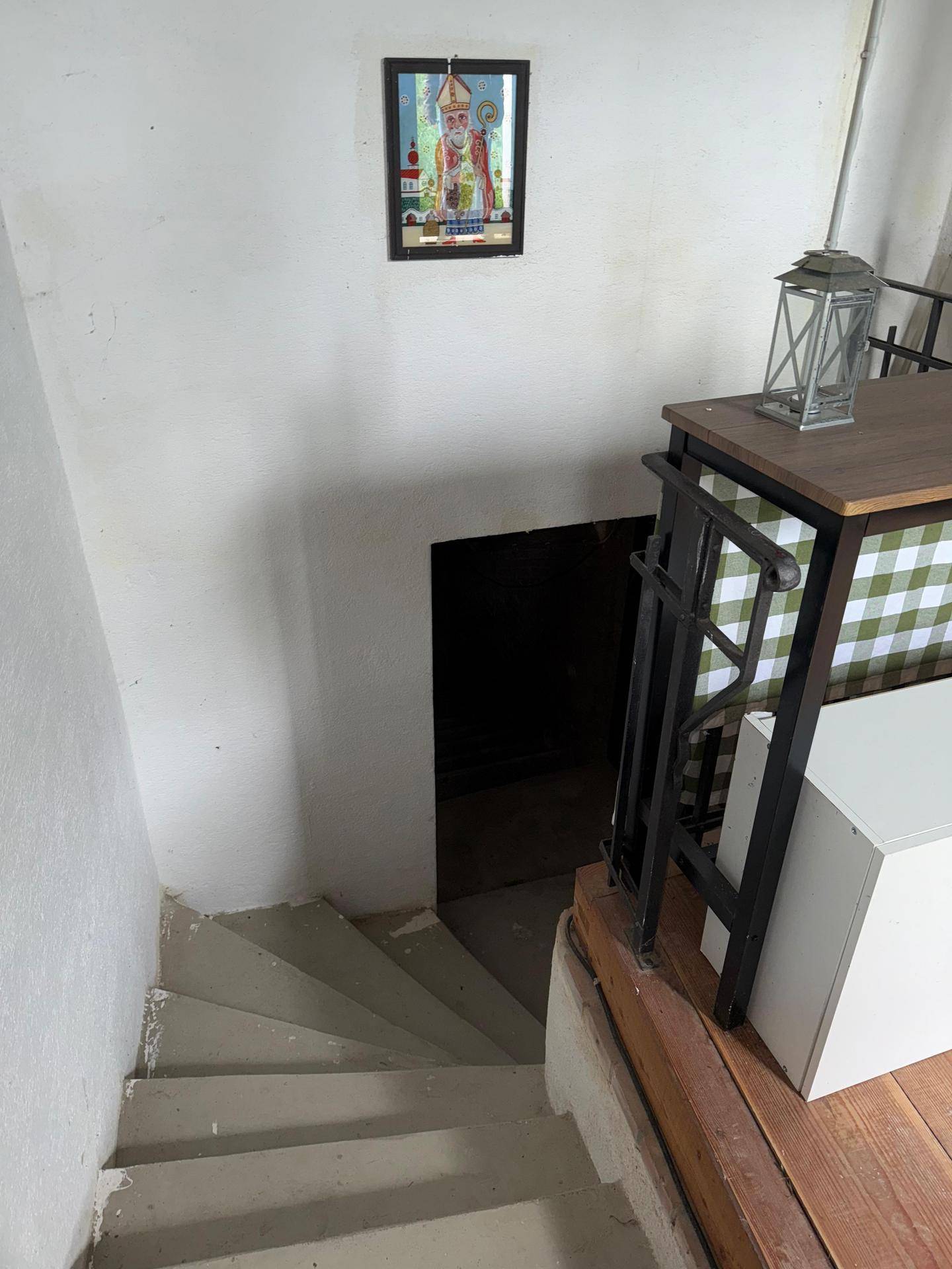 Treppe führt hinunter in einen dunklen Kellerbereich, beleuchtet von einem kleinen Licht.