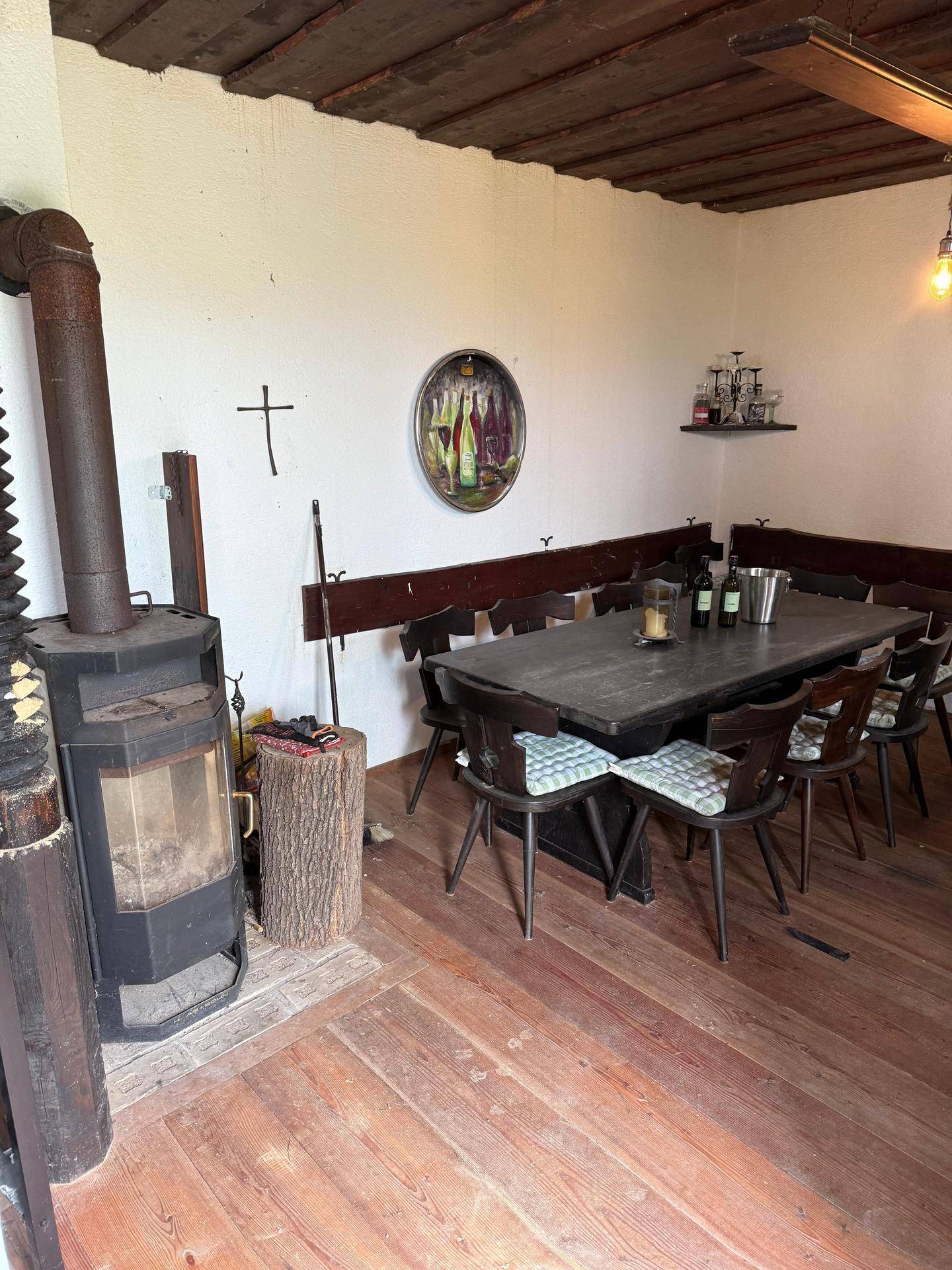Rustikaler Essbereich mit großem Holztisch und einem Holzofen für gemütliche Wärme.