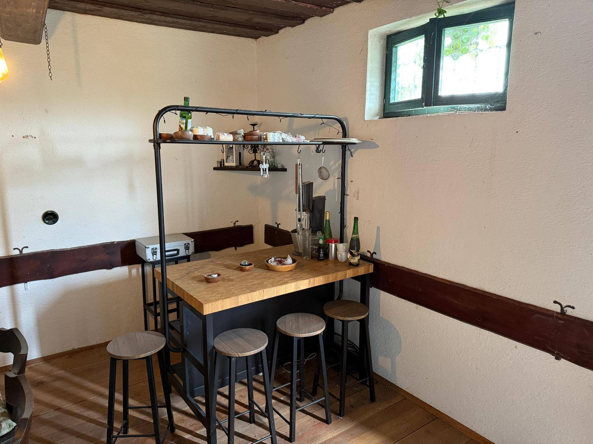 Kleine, rustikale Bar mit Holzarbeitsplatte und Hockern, integriert in den Essbereich.