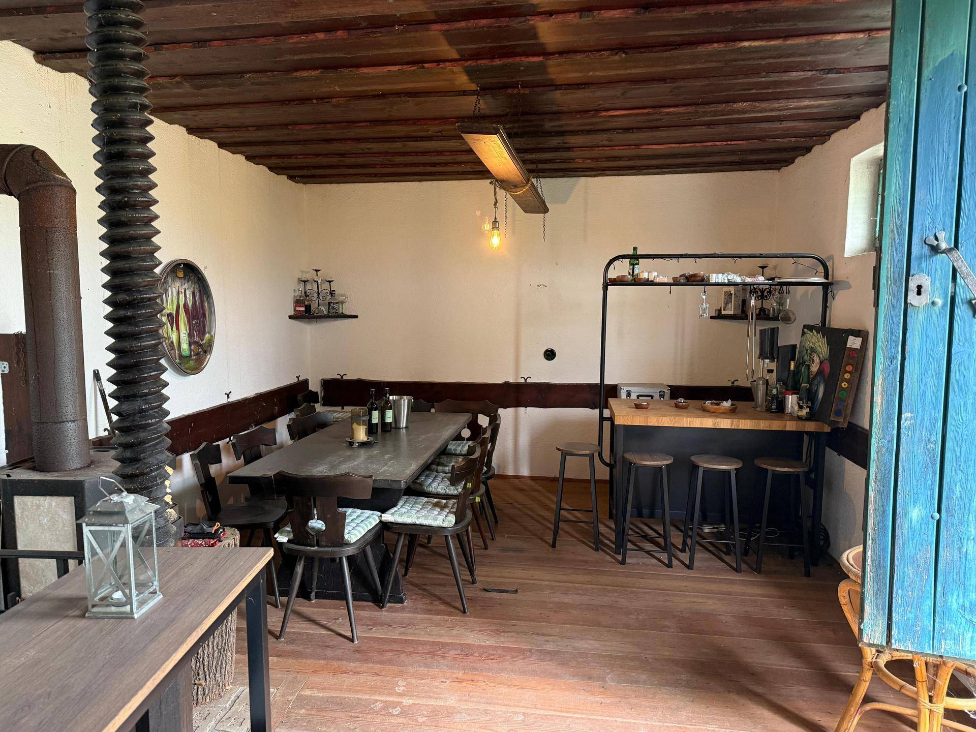 Gemütlicher Essbereich mit Holztisch, Bänken und einer kleinen Bar unter Holzbalkendecke.