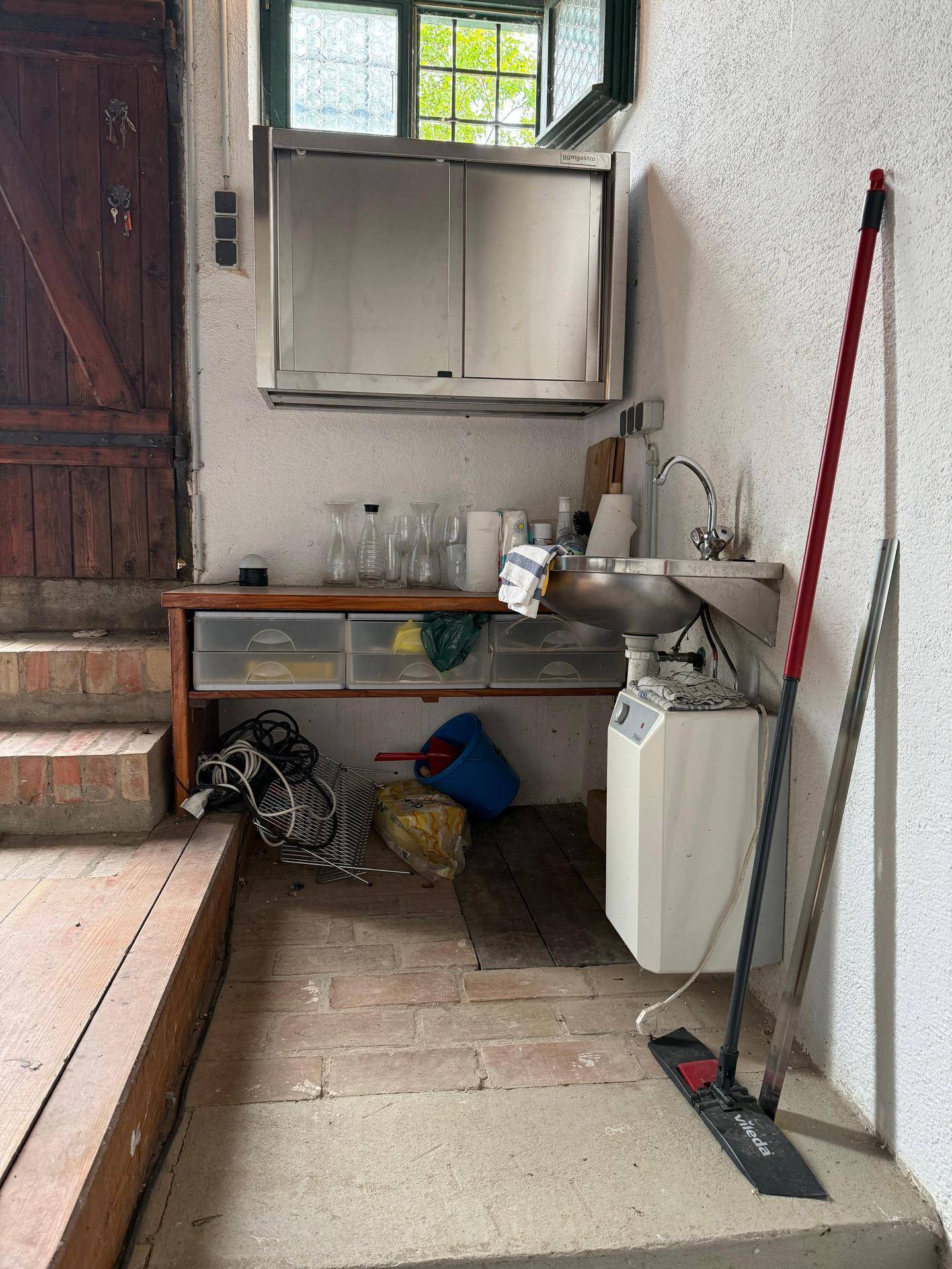 Funktionaler Hauswirtschaftsraum mit Spülbecken, Schränken und Reinigungsutensilien.