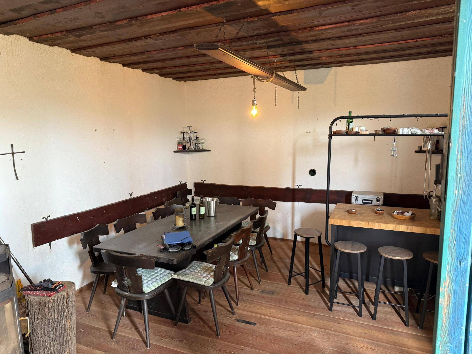 Rustikaler Essbereich mit Holztisch, Bänken und einer kleinen Bar in einem traditionellen Raum.
