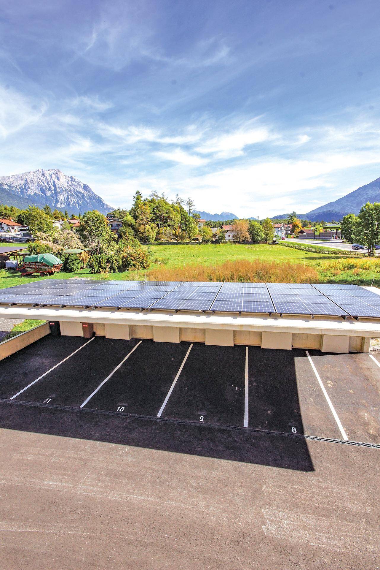 Außenansicht des Parkplatzes mit Solaranlage auf dem Carport und weitem Blick auf die Berglandschaft.