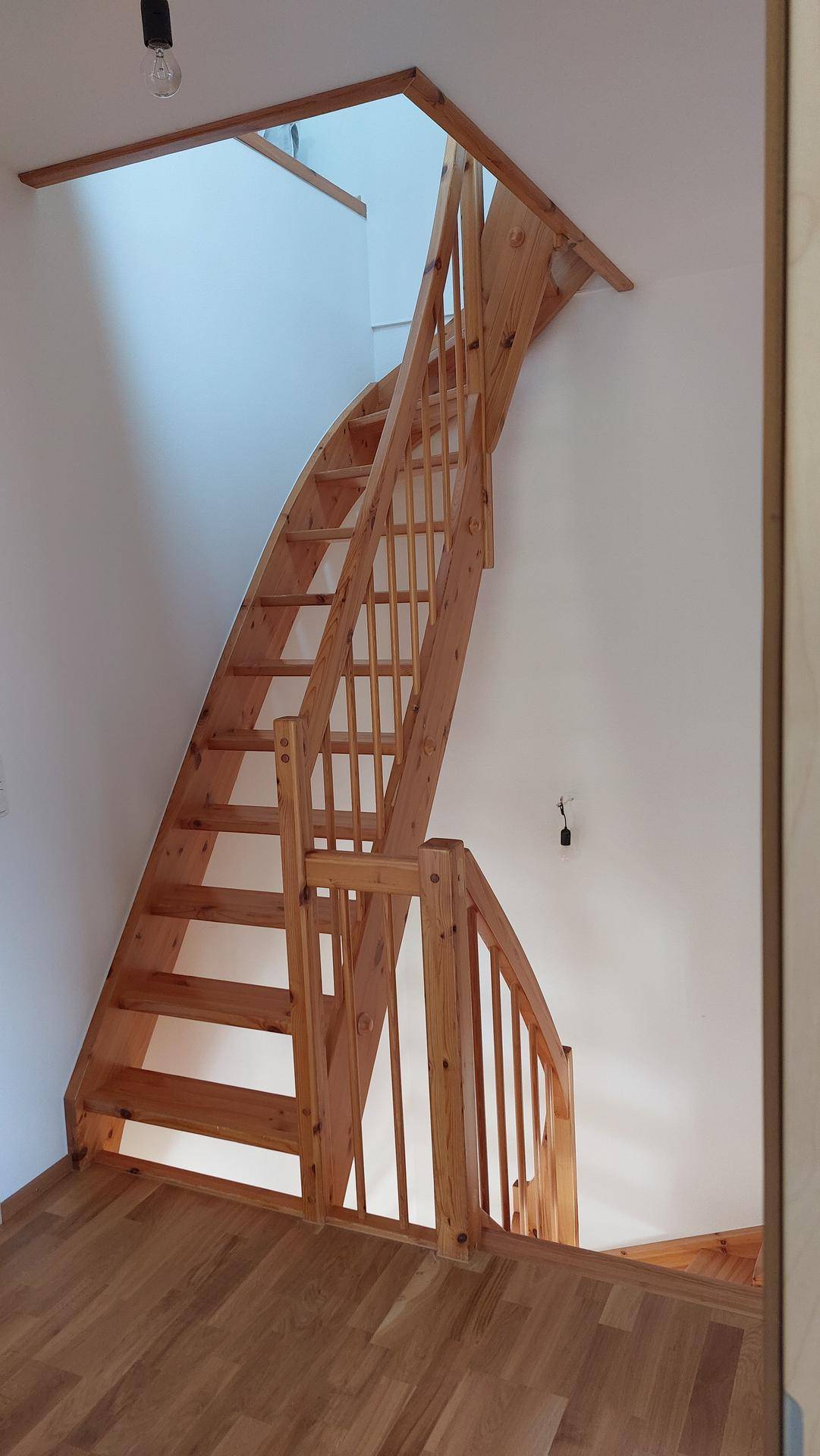 Helle Holztreppe mit offenem Design, die die Stockwerke des Hauses verbindet.