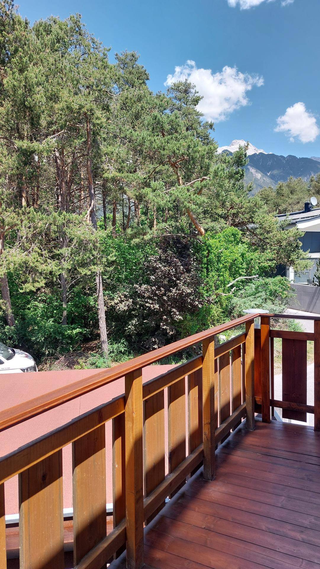 Blick vom Holzbalkon auf den Wald und die umliegende Berglandschaft.