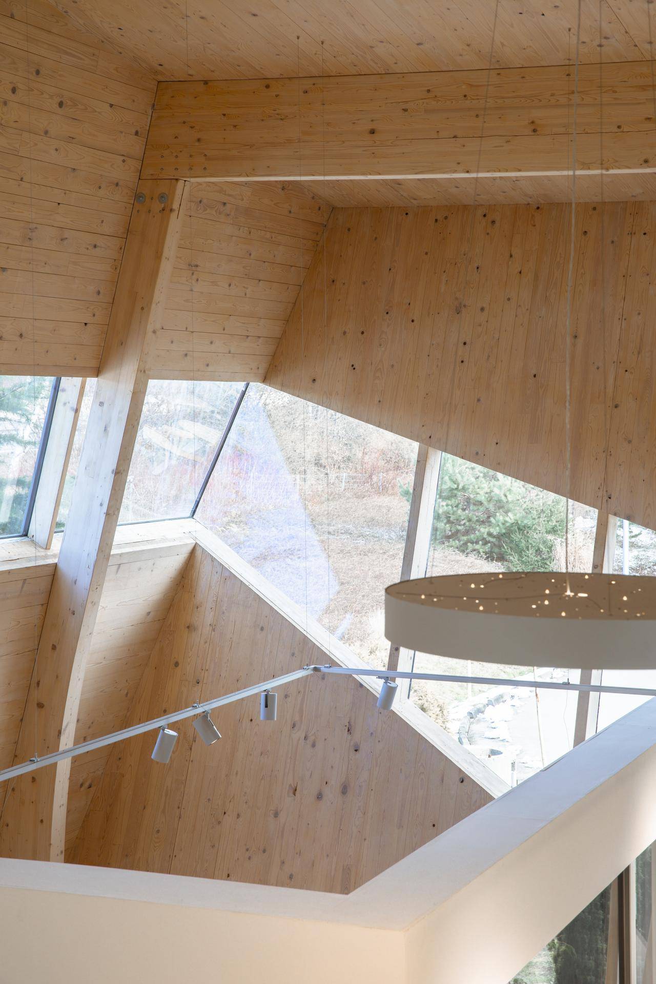 Detailansicht der modernen Holzarchitektur mit großen, schrägen Fenstern, die viel Tageslicht hereinlassen.