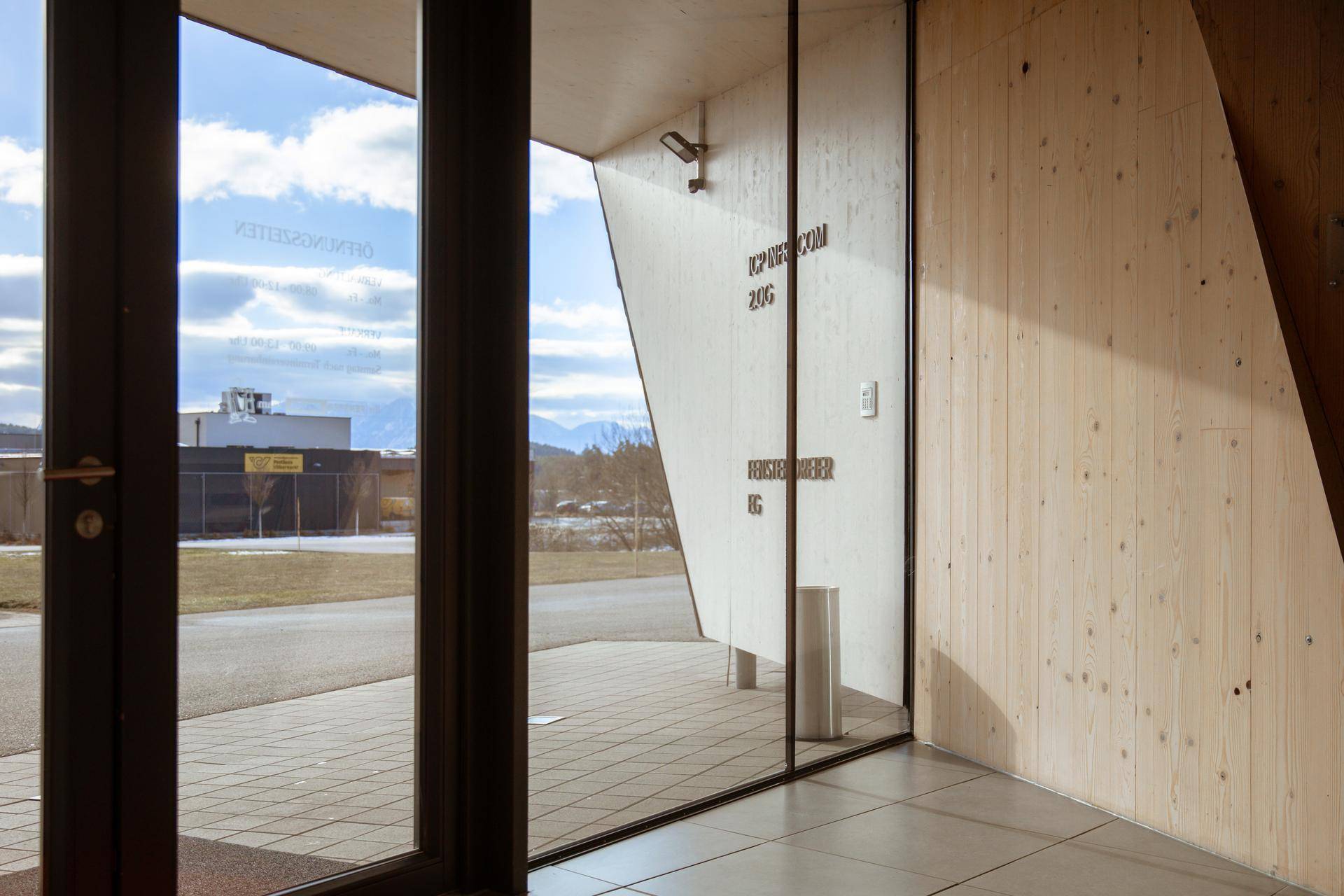 Heller Eingangsbereich mit großen Glastüren und Blick auf die bergige Landschaft durch die Fenster.
