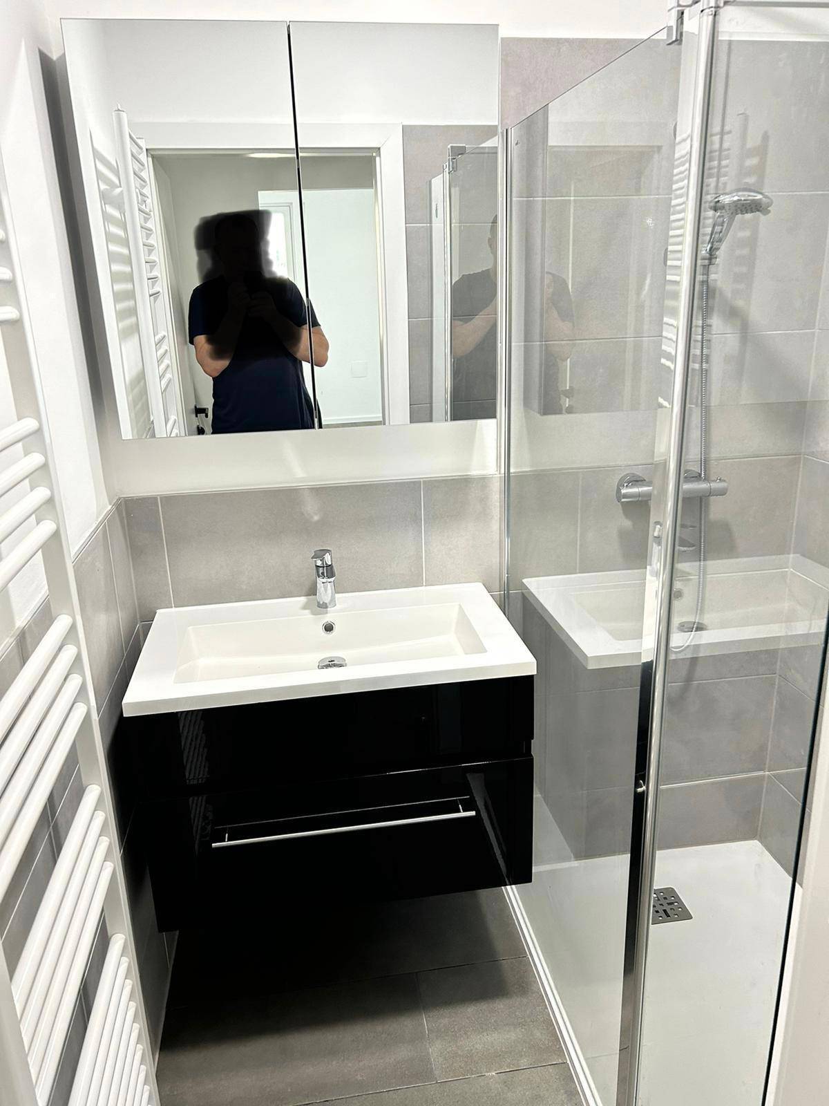 Modernes Badezimmer mit Duschkabine, Waschbecken und beheiztem Handtuchhalter.