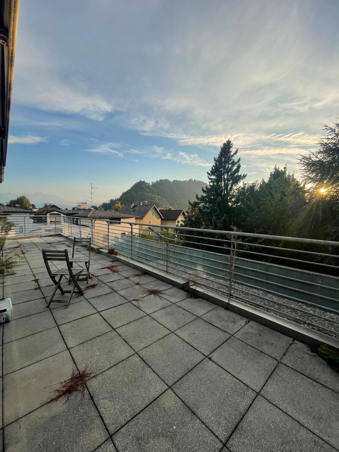 Geräumige Terrasse mit Fliesenboden, Metallgeländer und weitem Bergblick.