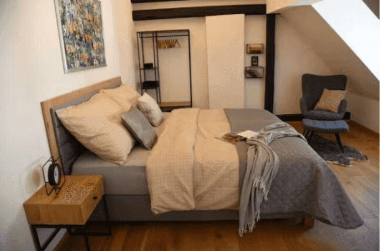 Schlafzimmer mit Doppelbett, Holzbalken, Dachschräge und modernem Dekor.