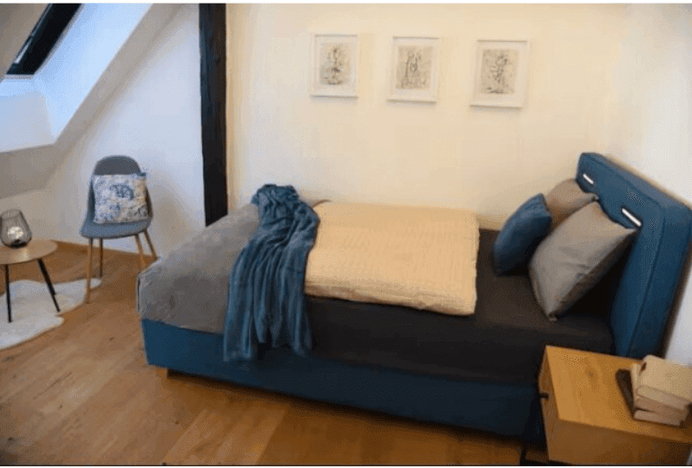 Gemütliches Schlafzimmer mit Einzelbett, Beistelltisch und Sessel in ruhiger Atmosphäre.