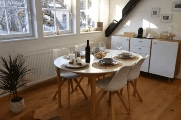 Gemütlicher Essbereich mit rundem Tisch, modernen Stühlen und viel Tageslicht durch die Fenster.