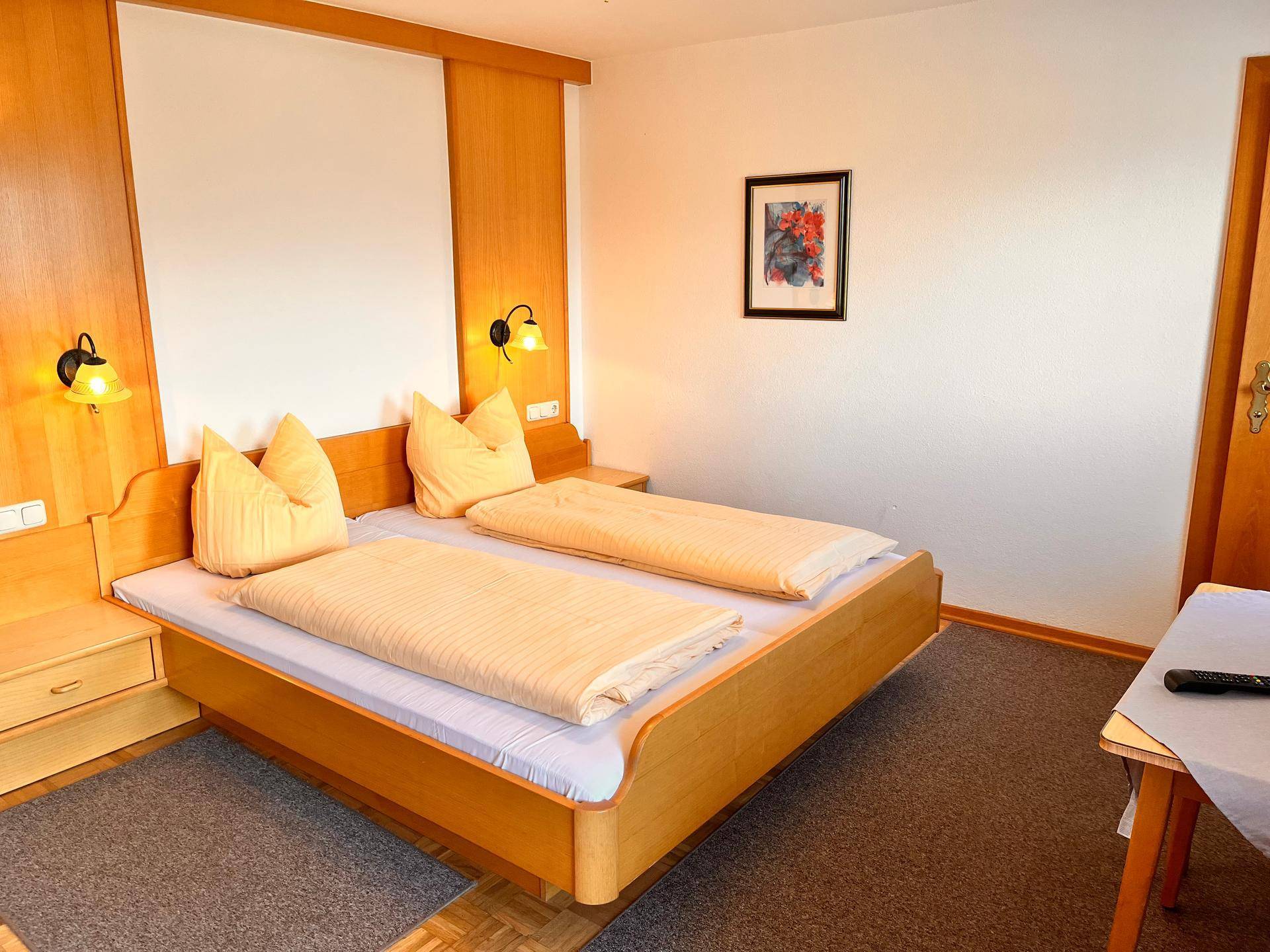 Gemütliches Schlafzimmer mit zwei Einzelbetten, Holzvertäfelung und Teppichboden.