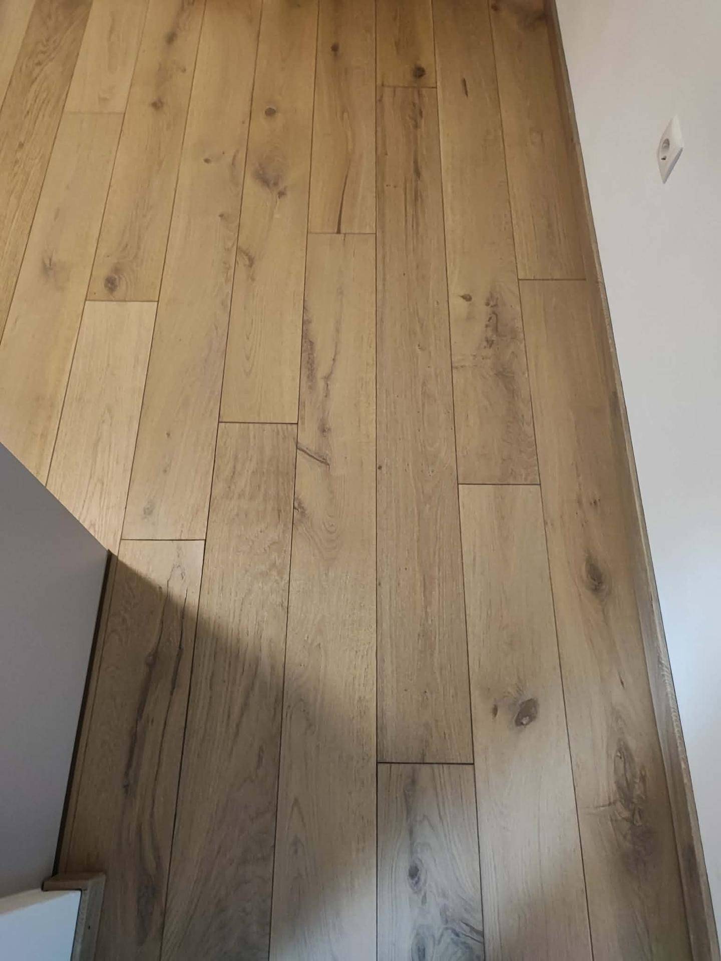 Nahaufnahme des hochwertigen Holzplankenbodens mit natürlicher Maserung und heller Oberfläche.