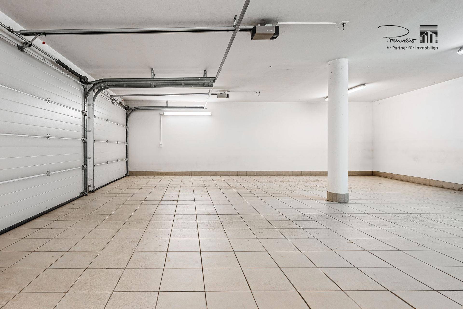 Geräumige Tiefgarage mit Fliesenboden und einem großen Garagentor, das viel Platz für Fahrzeuge bietet.