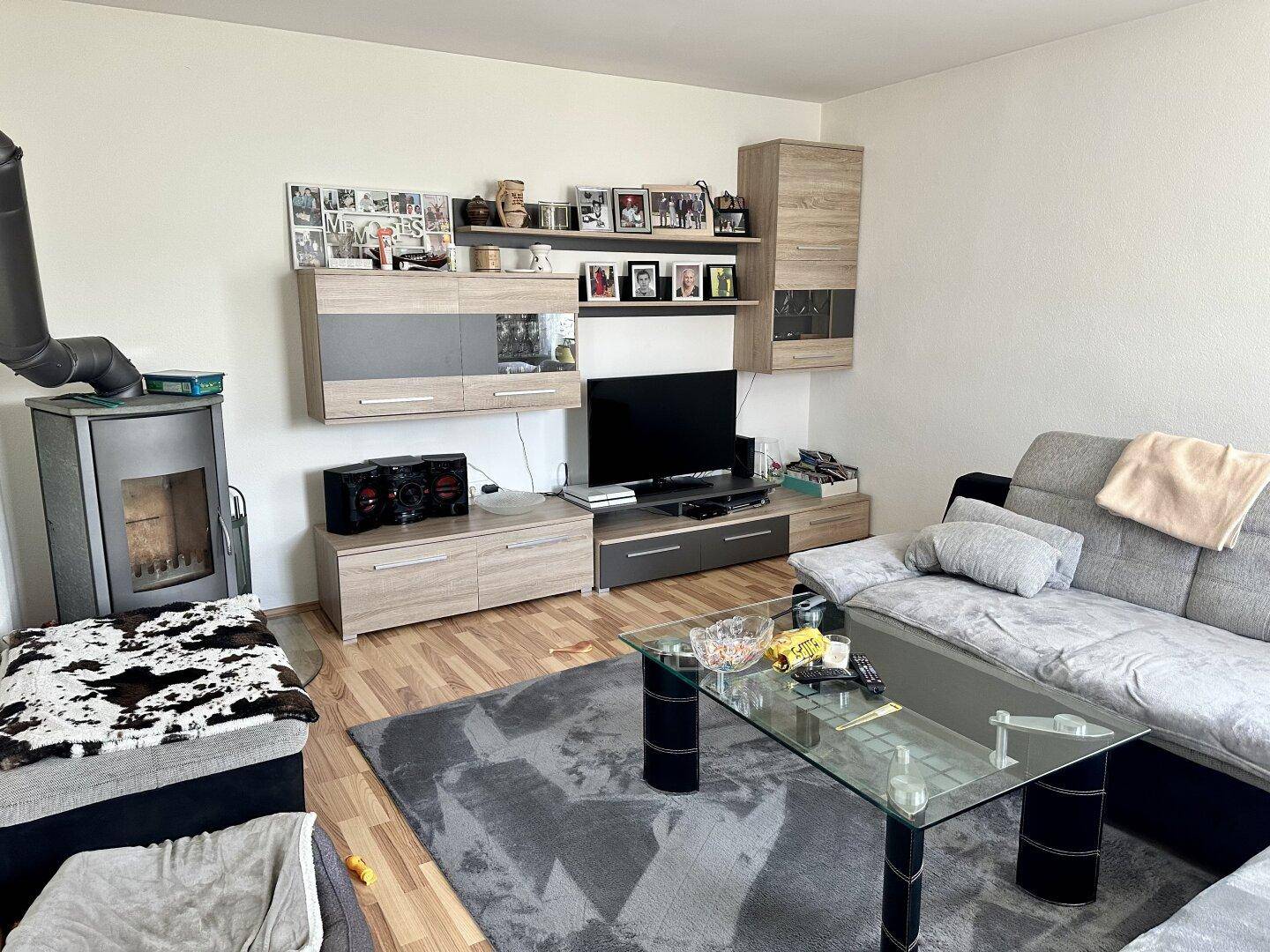 Gemütliches Wohnzimmer mit Kaminofen, Laminatboden und moderner Wohnwand.