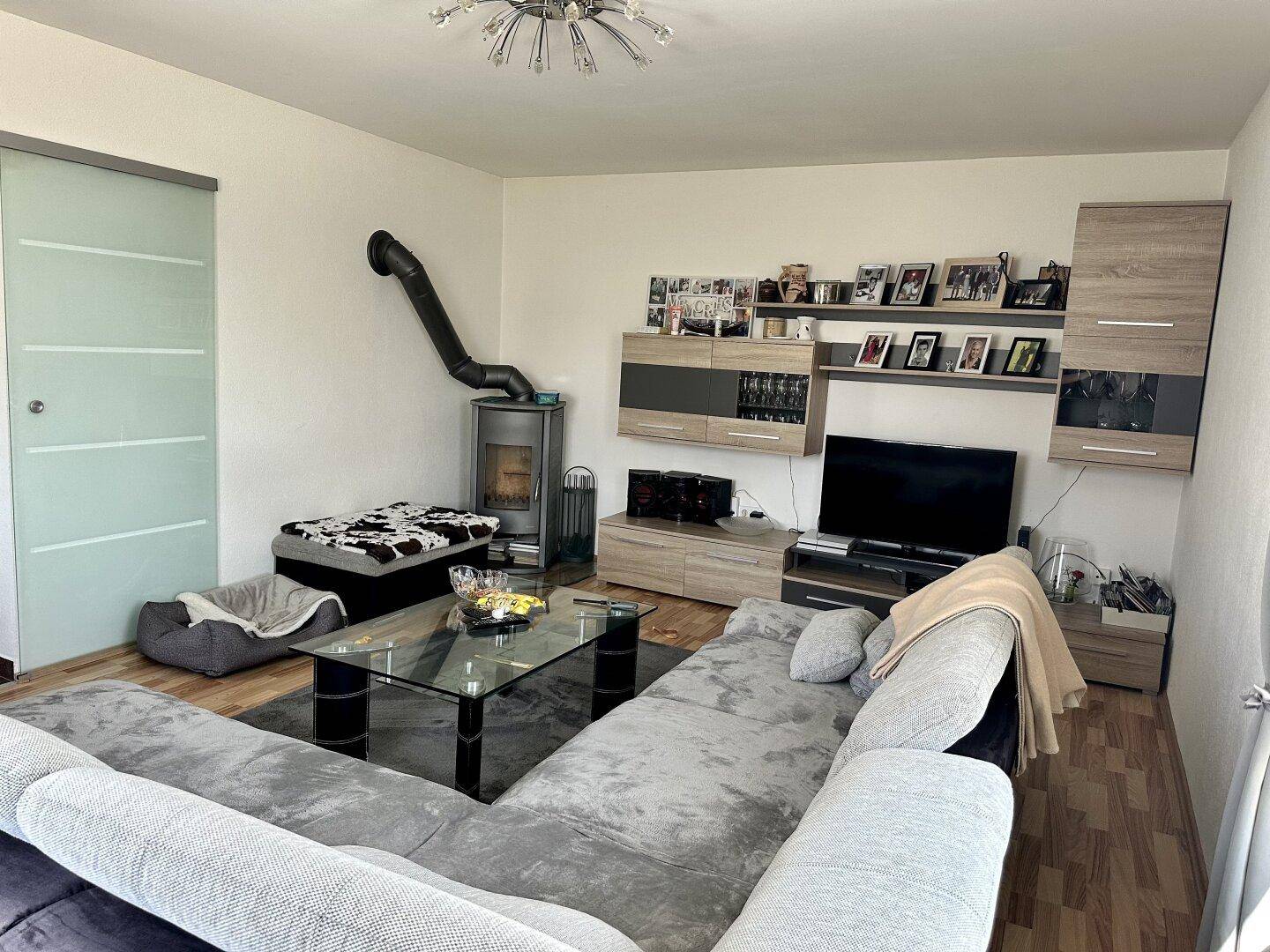 Geräumiges Wohnzimmer mit bequemer Eckcouch, Kaminofen und stilvoller Einrichtung.
