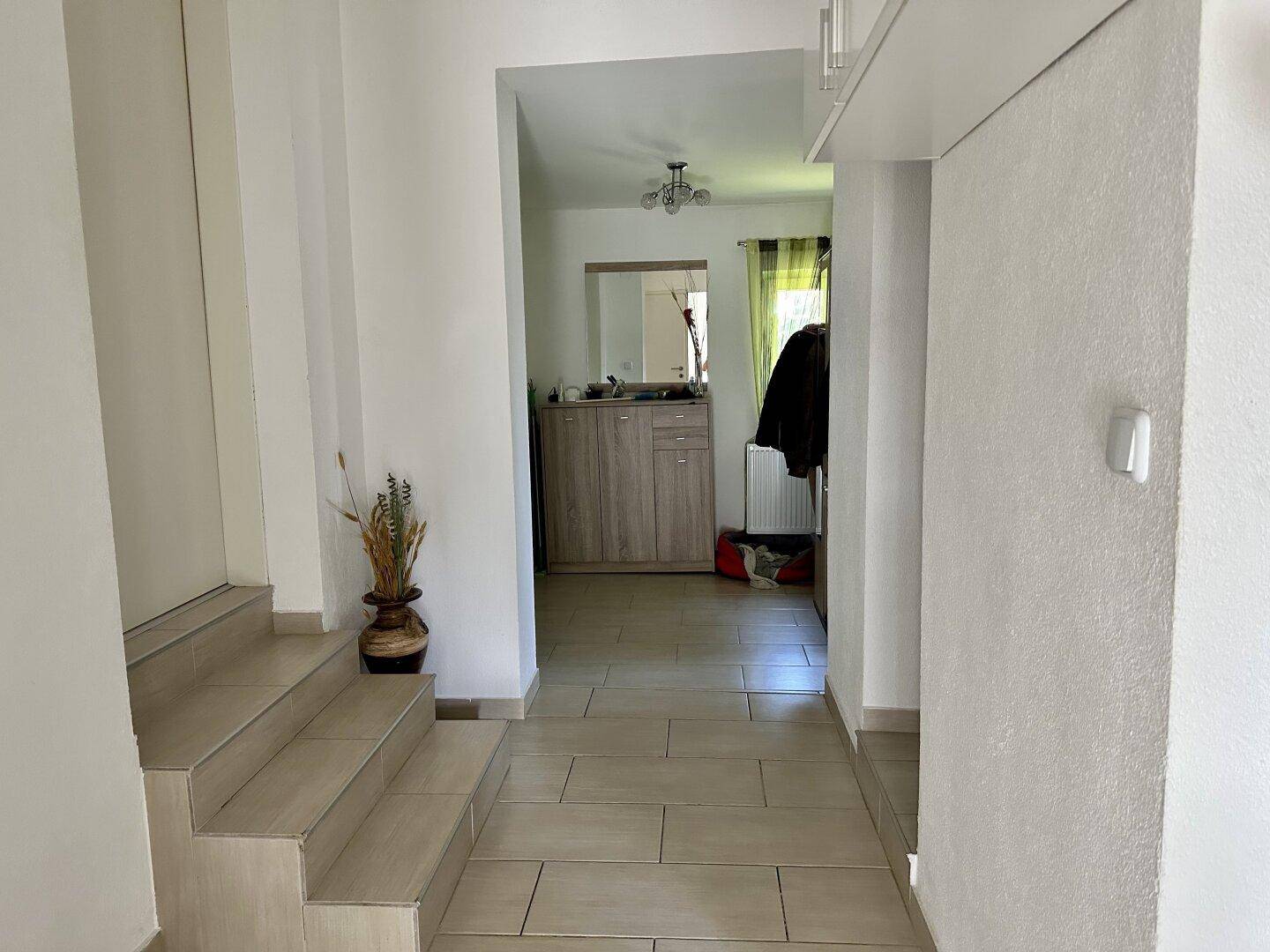 Heller Eingangsbereich mit Fliesenboden und Treppe, die in die oberen Stockwerke führt.