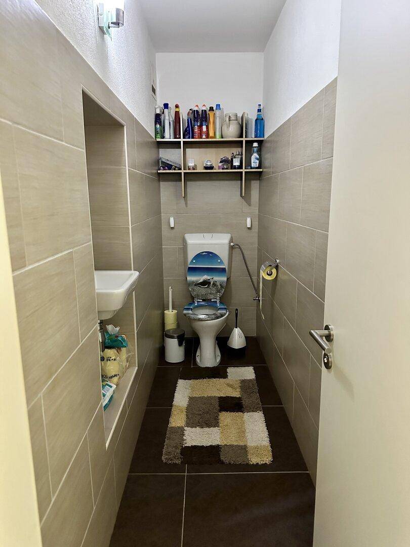 Kompaktes Gäste-WC mit modernen Fliesen und einem kleinen Waschbecken.
