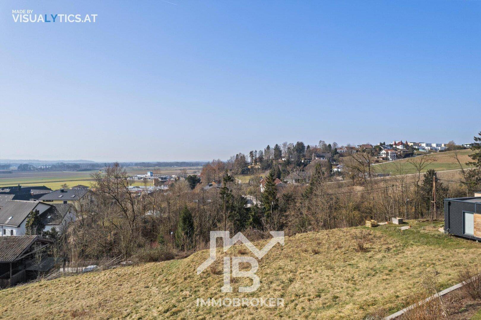 Weitläufiges, leicht abfallendes Grundstück mit Blick auf eine grüne Landschaft und entfernte Häuser.