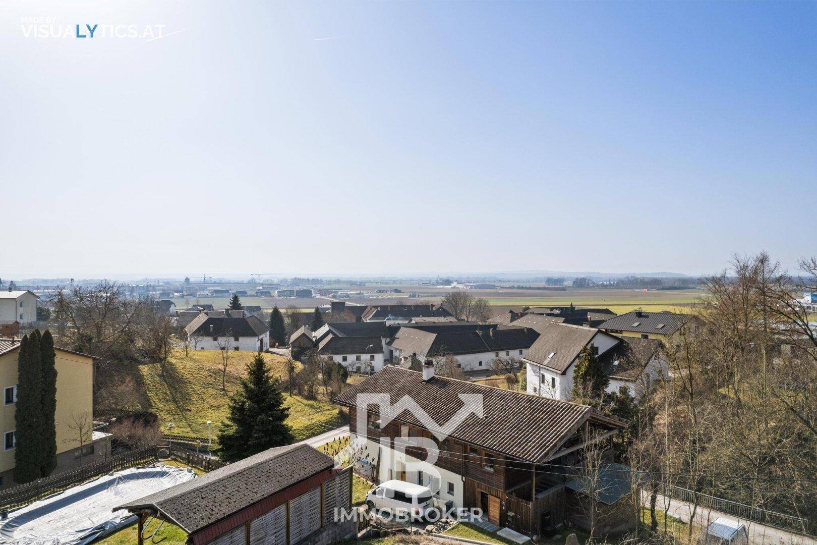 Panoramablick über eine malerische Wohnsiedlung mit traditionellen Häusern und weiten Feldern.