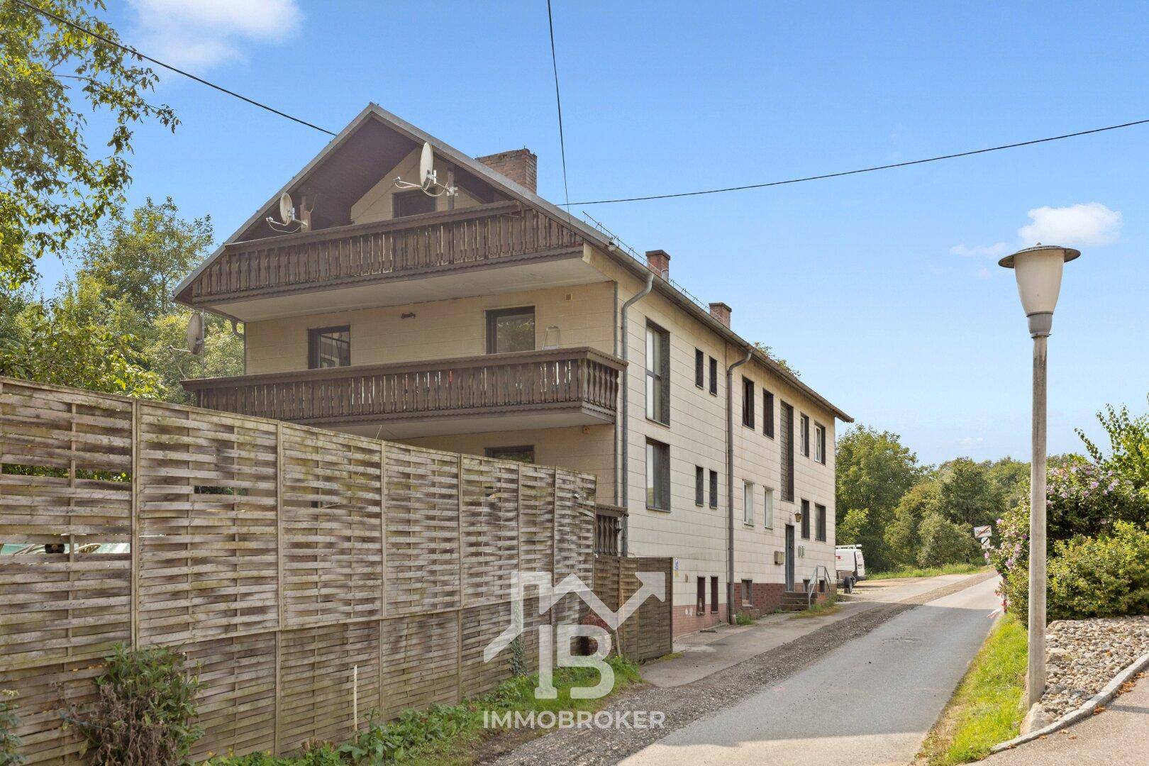 Seitenansicht des Gebäudes mit Holzbalkonen und einem Holzzaun entlang der Straße.