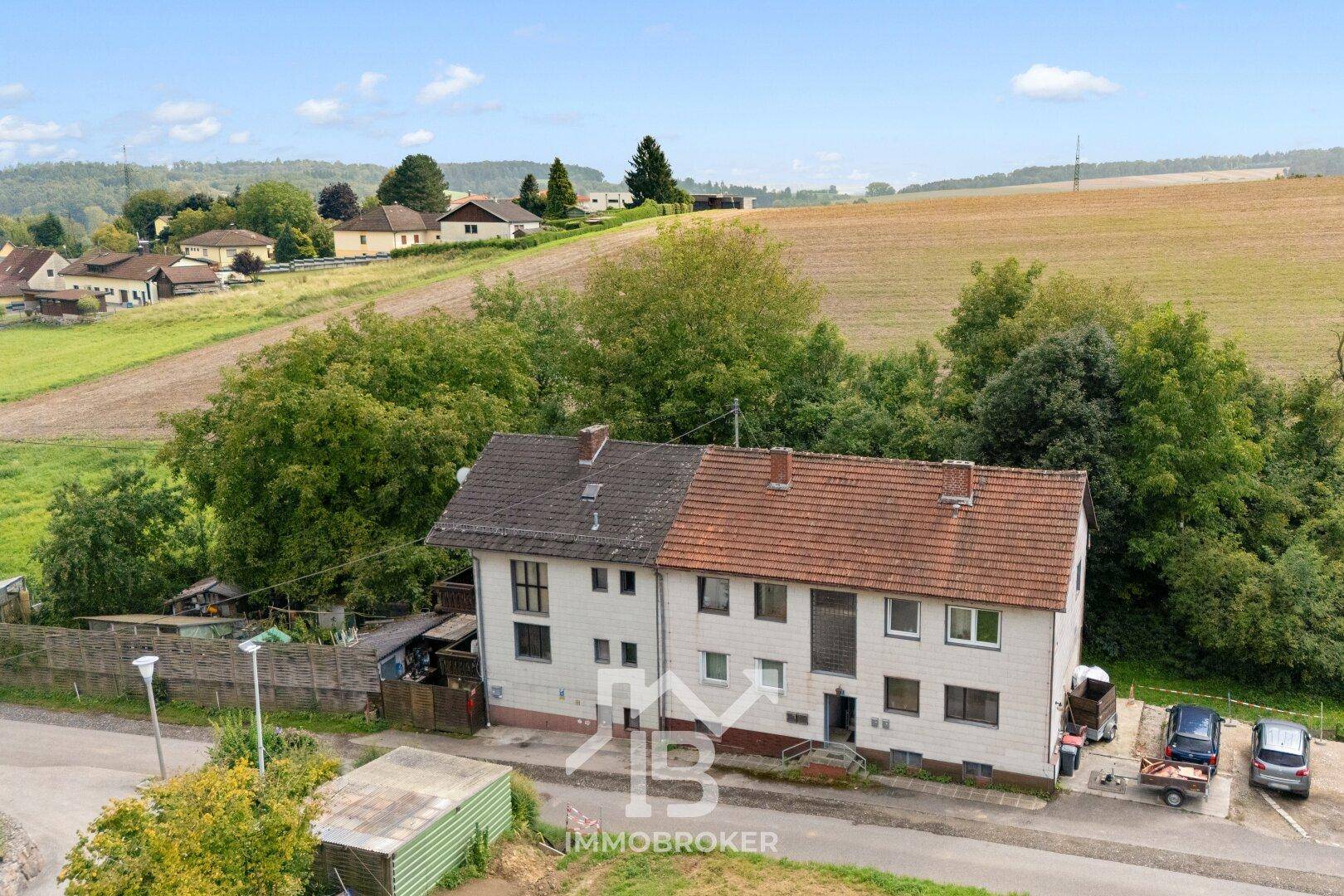 Überblick über das Mehrfamilienhaus und die ländliche Umgebung mit Feldern und Bäumen.