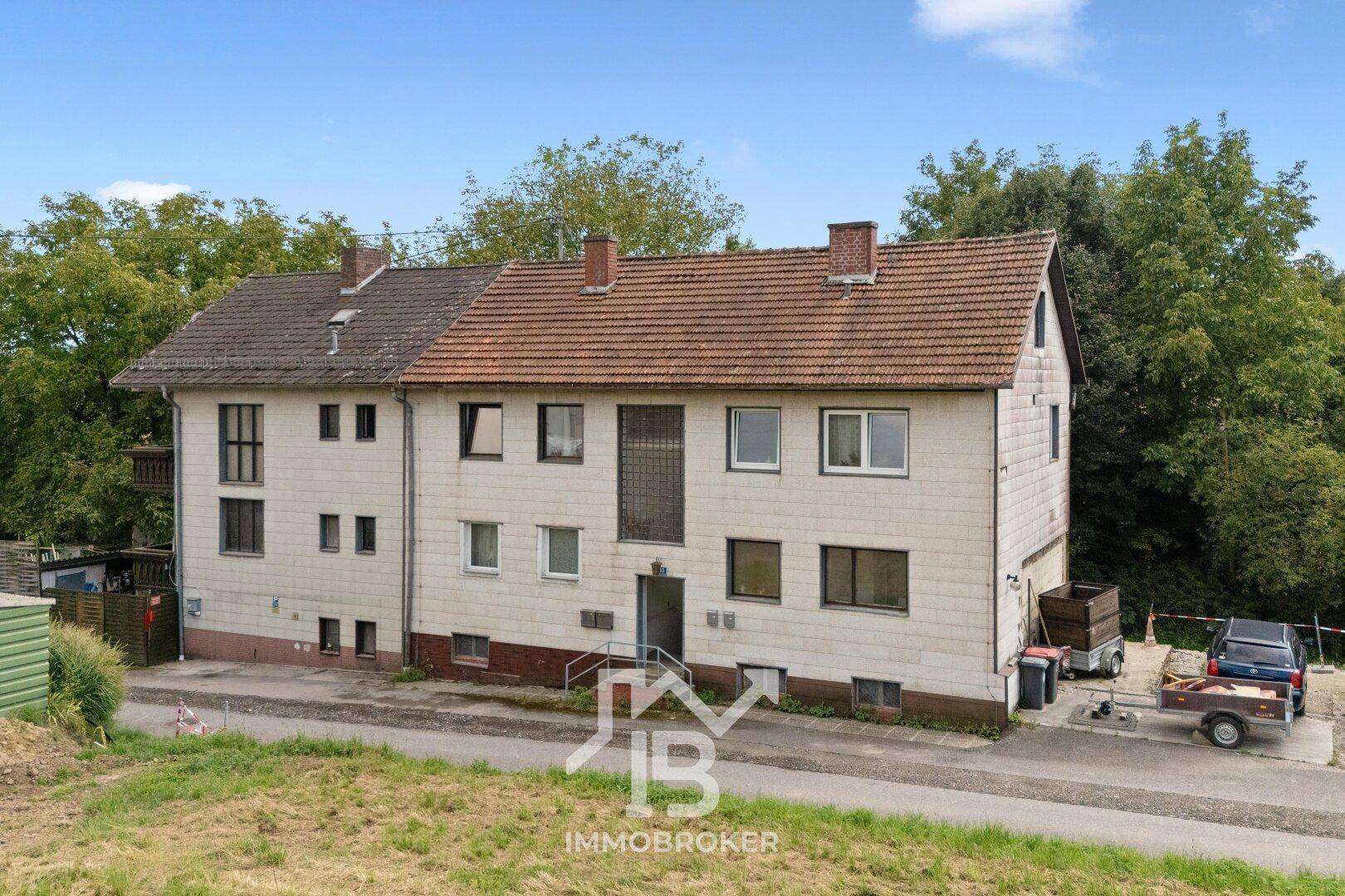 Ansicht des Mehrfamilienhauses mit mehreren Wohneinheiten und Parkmöglichkeiten vor dem Gebäude.