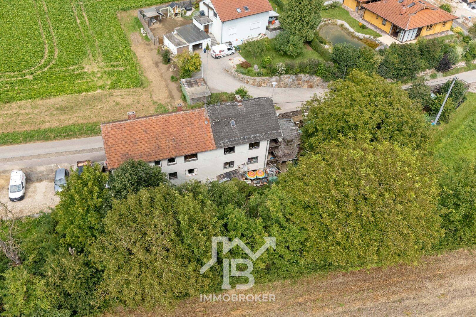 Weitläufige Luftaufnahme des Anwesens, eingebettet in eine grüne Landschaft mit weiteren Häusern.