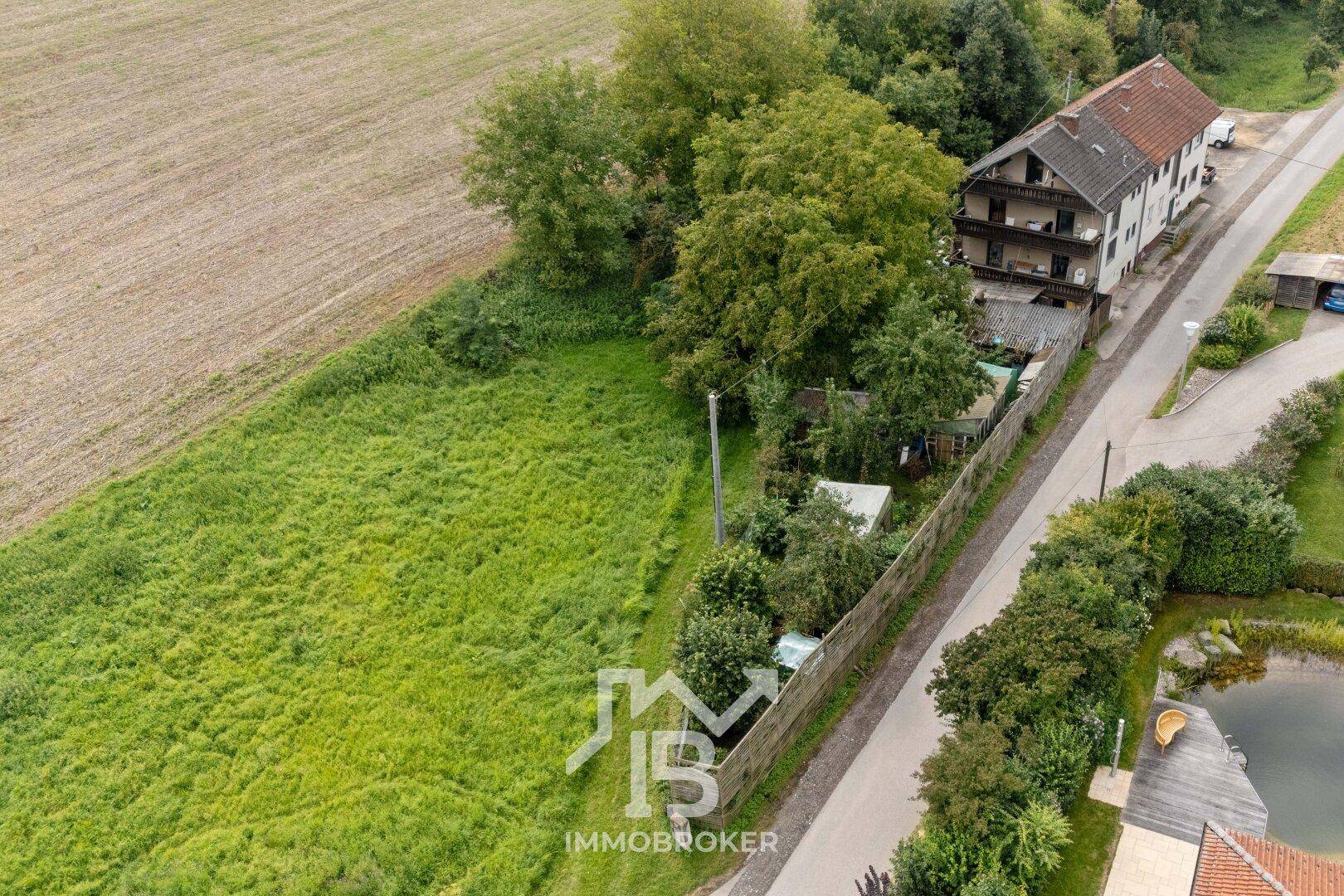 Luftaufnahme des Grundstücks mit einem großen Feld und dem Mehrfamilienhaus im Hintergrund.