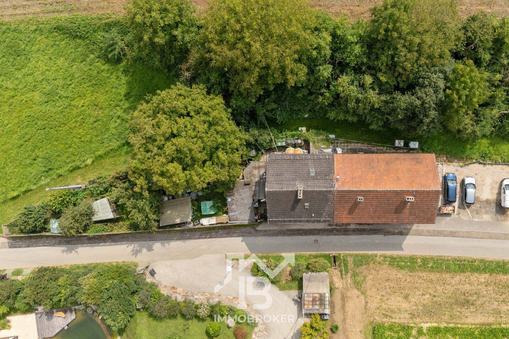 Vogelperspektive des Mehrfamilienhauses mit angrenzenden Gärten und Parkplätzen.