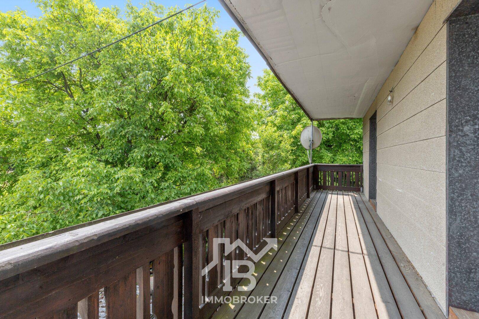 Geräumiger Holzbalkon mit Blick ins Grüne, ideal zum Entspannen im Freien.