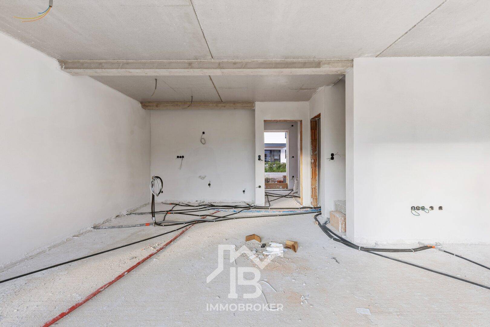 Rohbau eines Raumes mit unverputzten Wänden und sichtbaren Installationen, wartet auf den Innenausbau.