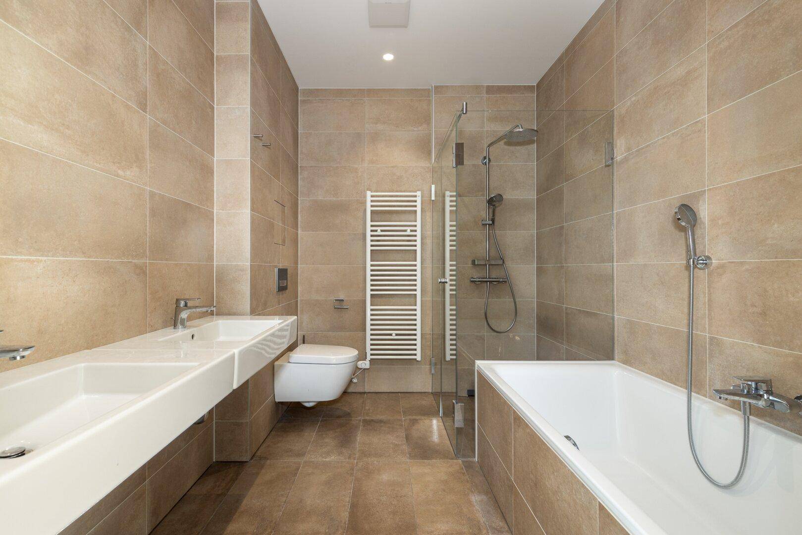 Geräumiges, modernes Badezimmer mit Doppelwaschbecken, Badewanne, Dusche und Wand-WC.