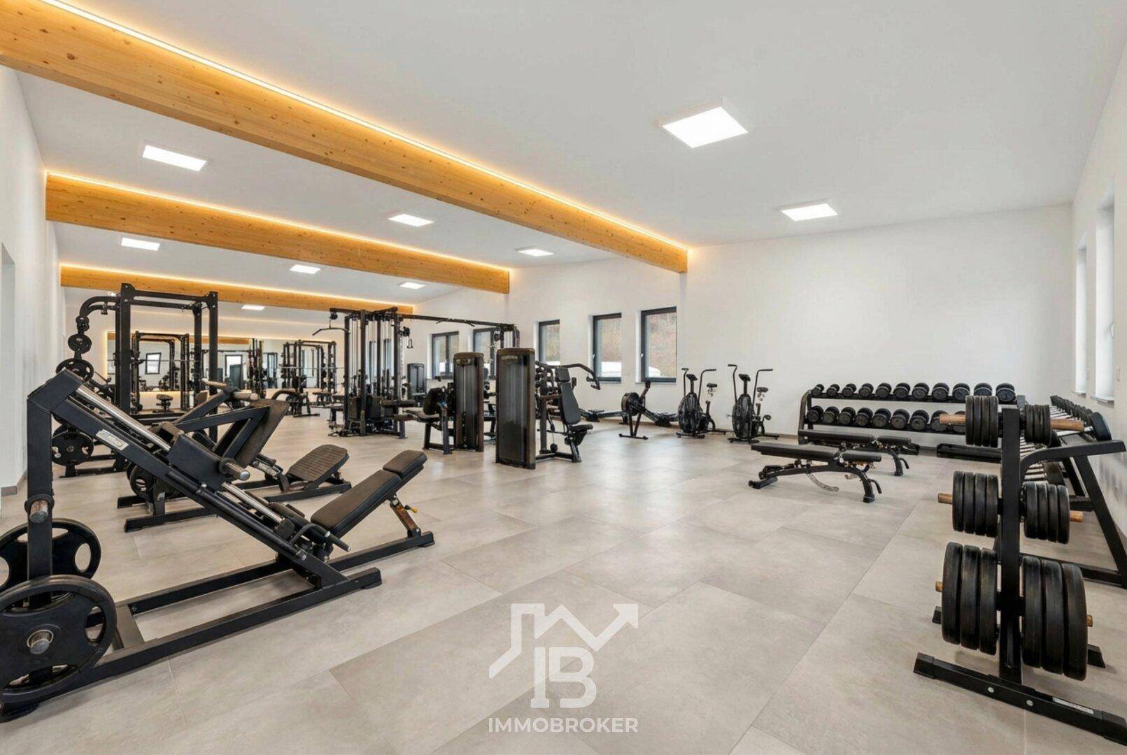 Umfassend ausgestatteter Fitnessraum mit einer breiten Palette an Trainingsgeräten und Hanteln, ideal für Krafttraining.