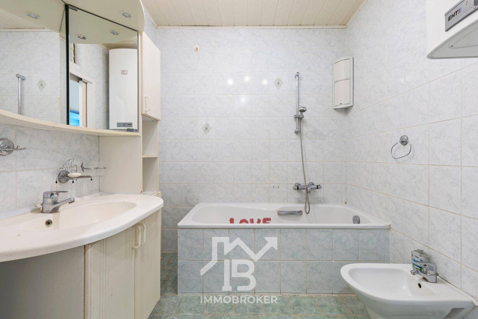 Badezimmer mit hellblauen Fliesen, Badewanne, Waschbecken und Bidet.