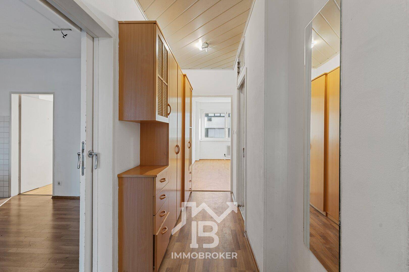 Geräumiger Flur mit Holzdecke, Parkettboden und praktischen Holzschränken.