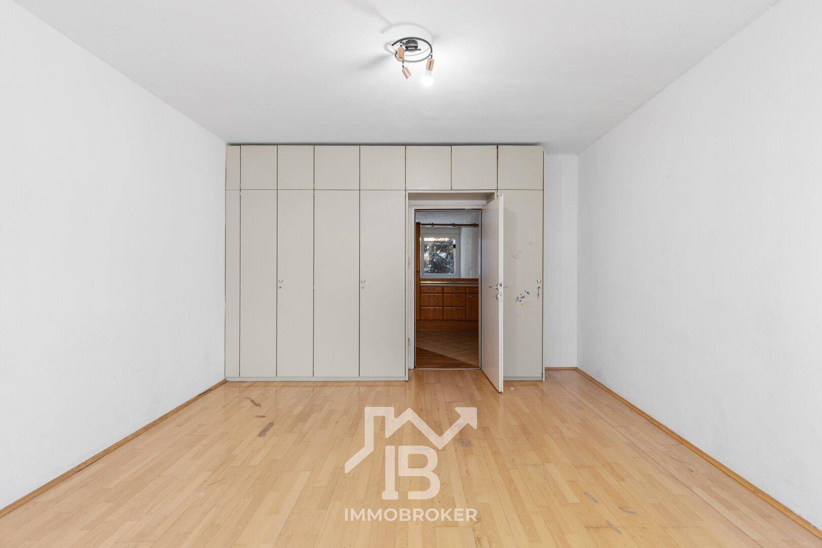 Helles Zimmer mit Parkettboden und integrierten Wandschränken, ideal als Schlafzimmer.
